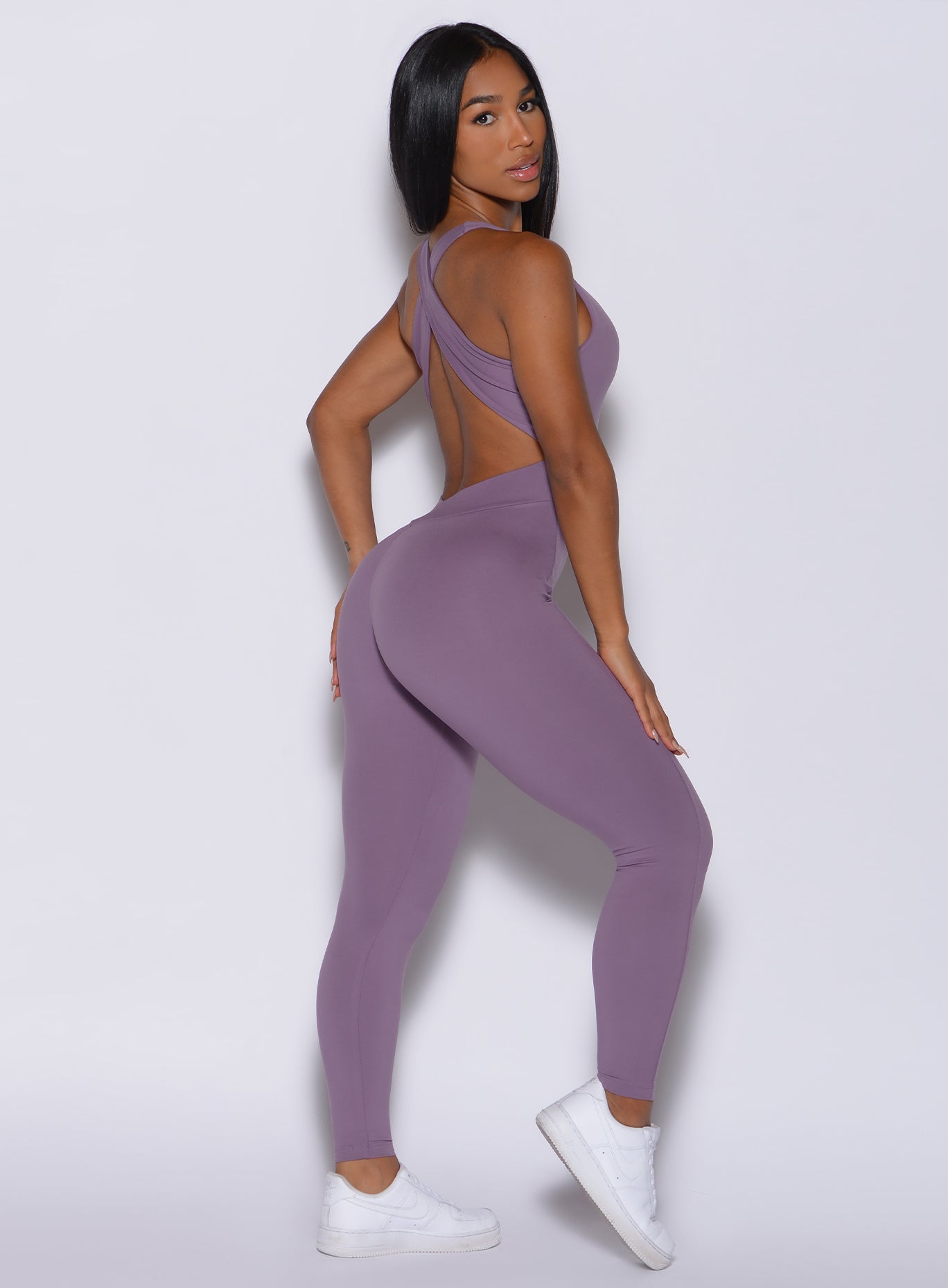 Right side  profile view of a model facing to her right wearing our laced bodysuit in Violet Frost color