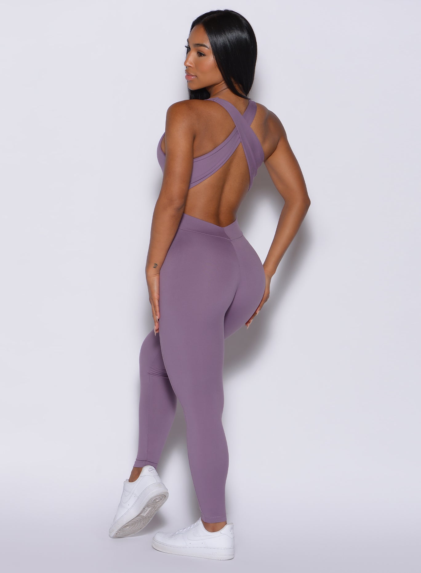 Back  profile view of a model in our laced bodysuit in Violet Frost color