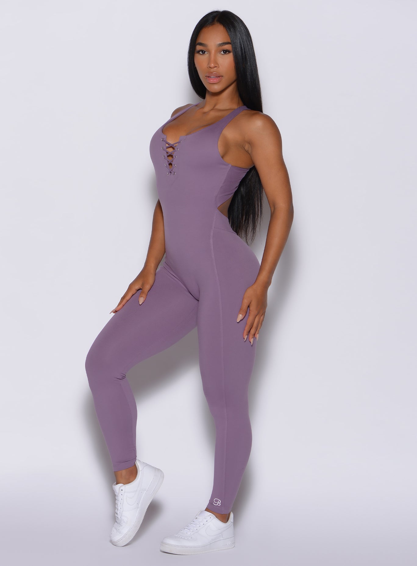 left side  profile view of a model angled slightly to her left wearing our laced bodysuit in Violet Frost color