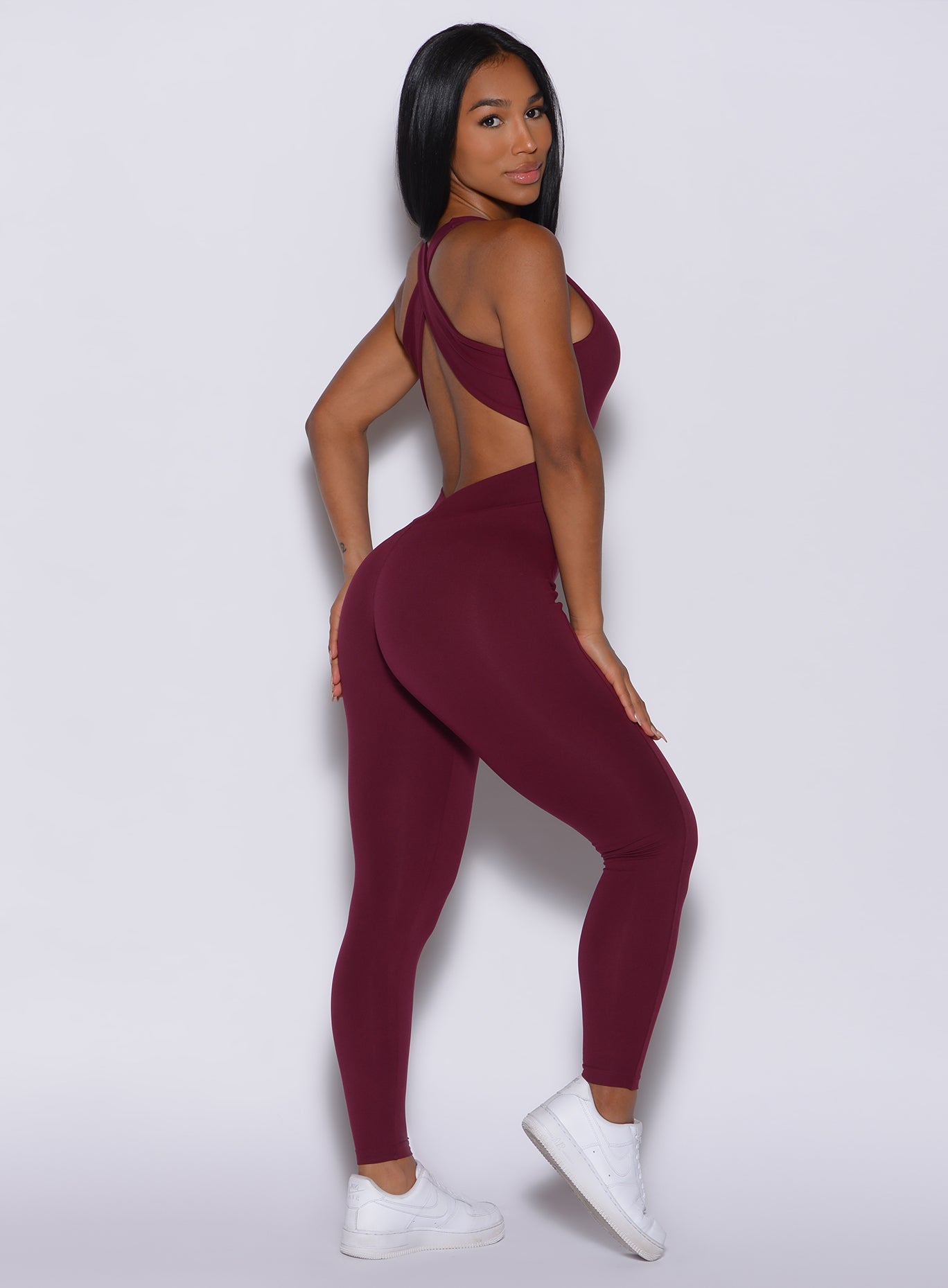 right side profile view of a model facing to her right wearing our ruby colored laced bodysuit 