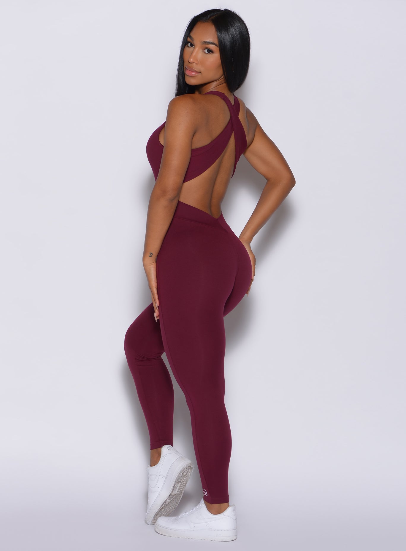 left side front profile view of a model angled left wearing our laced bodysuit in ruby color