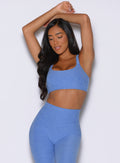 front profile view of a model with both hands resting on top of her head wearing the Halo Sports Bra in boss blue color