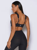 back left side view of a model facing to the left side wearing the Halo Sports Bra in Heathered Black color