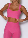 close up front view of a model wearing the Halo Sports Bra in pink glo color