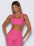 front profile view of a model wearing the Halo Sports Bra in pink glo color
