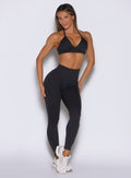 front view of a model with both hands resting on her thighs wearing the Hardbody Leggings in Heathered Black color