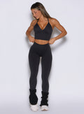 front profile view of a model adjusting the waistband wearing the Hardbody Leggings in Heathered Black color