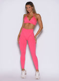 frontal view of a model wearing the Hardbody Leggings in Neon Flame color paired with the matching bra 