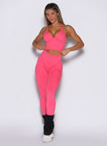 front view of a model adjusting the waistband wearing the Hardbody Leggings in Neon Flame color