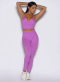 front view of a model with both hands resting behind her head wearing the Hardbody Leggings in Purple Rain color