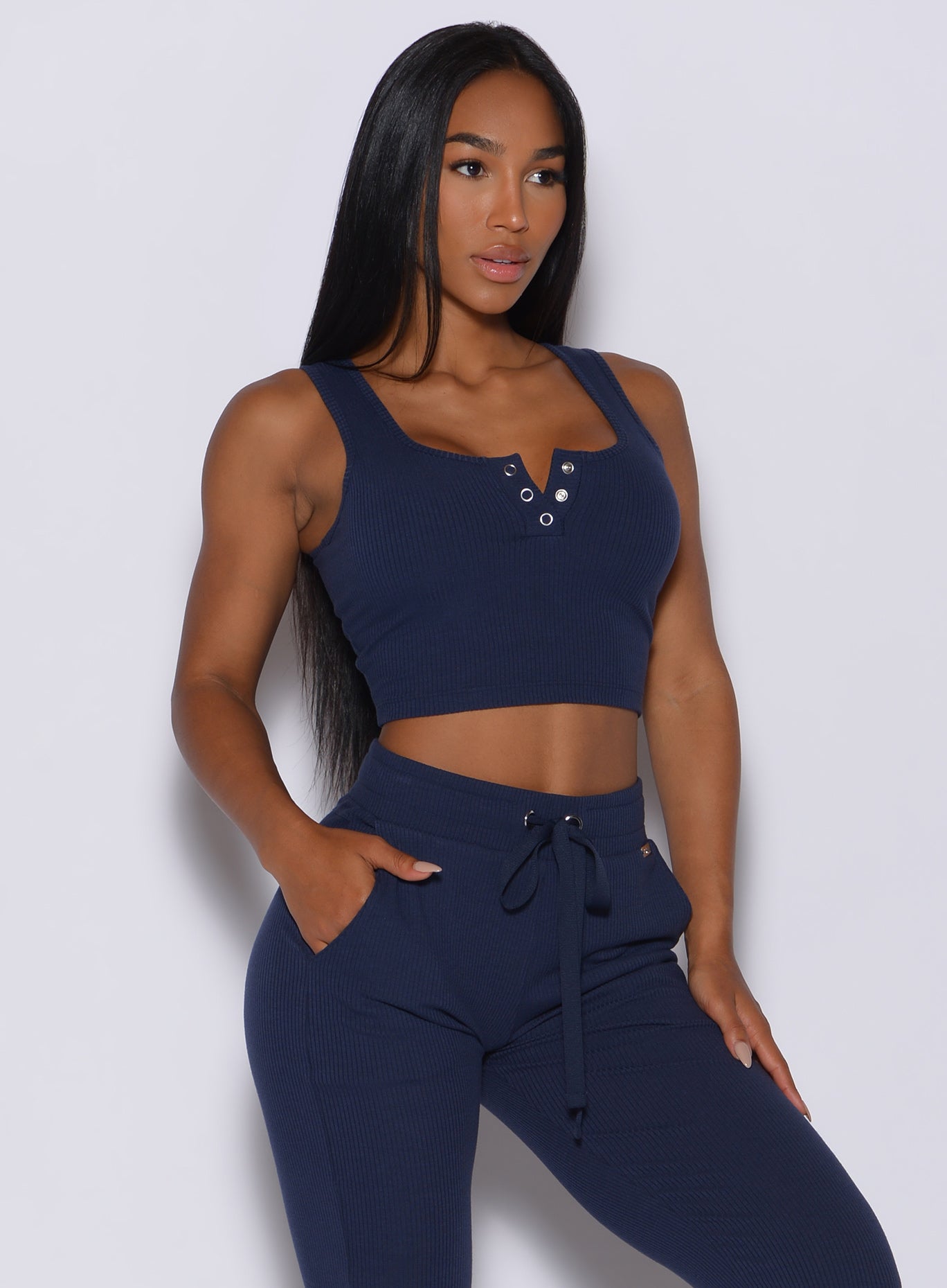 front profile view of a model with her left hand in pocket wearing our henley long bra in navy and a matching joggers