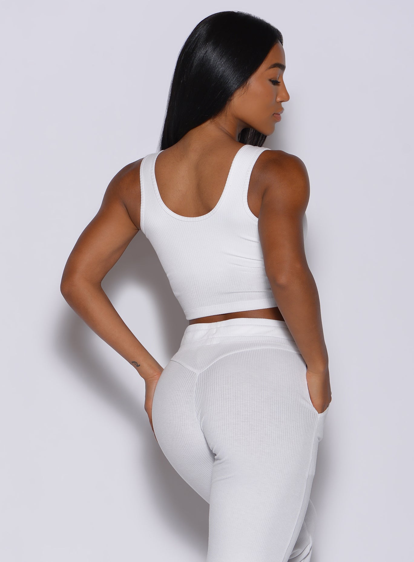 Back profile view of a model facing to her right wearing our white henley long bra  and a matching leggings 
