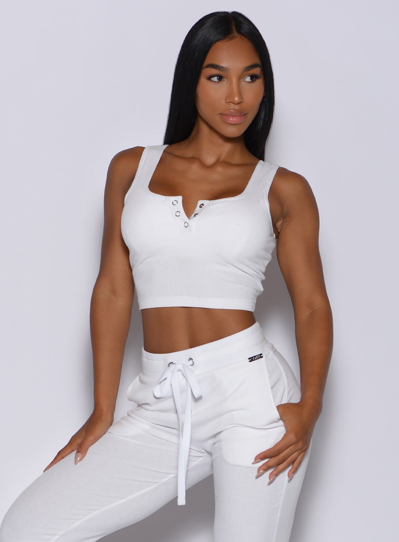 Front  profile view of a model facing to her left wearing our white henley long bra and a matching joggers