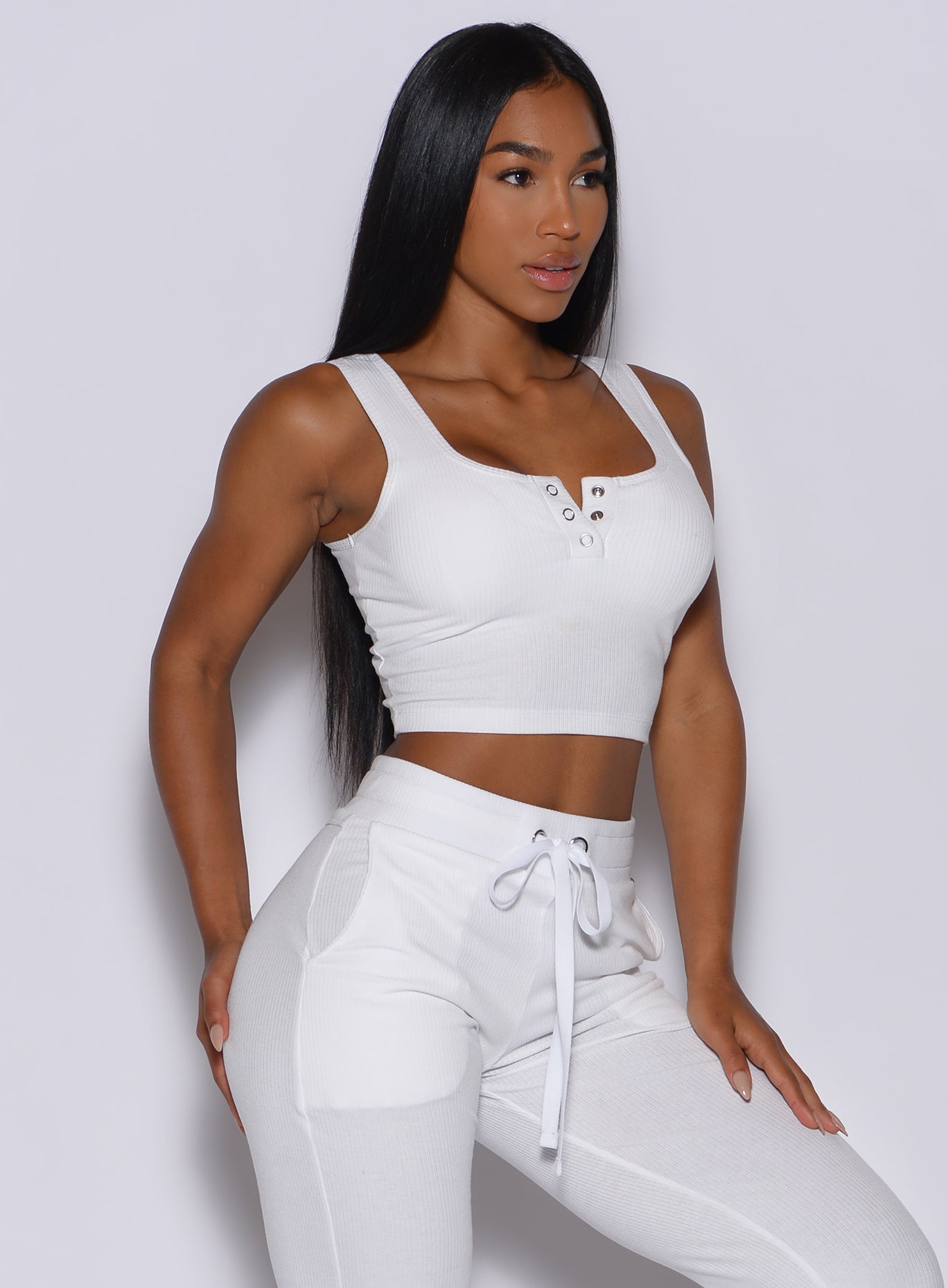 right side  profile view of a model angled right wearing our white henley long bra and a matching joggers