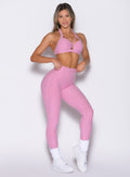 front profile view of a model with both hands on the waistband wearing the Movement Leggings in Candy Pink color