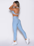 left side profile view of a model wearing the Movement Leggings in Blue Mist color paired with the matching bra