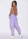 back left side profile view of a model looking over her shoulder wearing the Movement Leggings in Sugared Lilac color