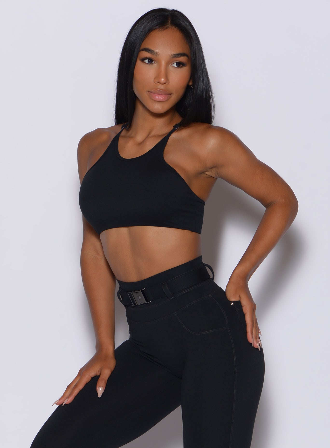 Front profile view of a model angled slightly to her left wearing our black high neck crop bra and a matching leggings