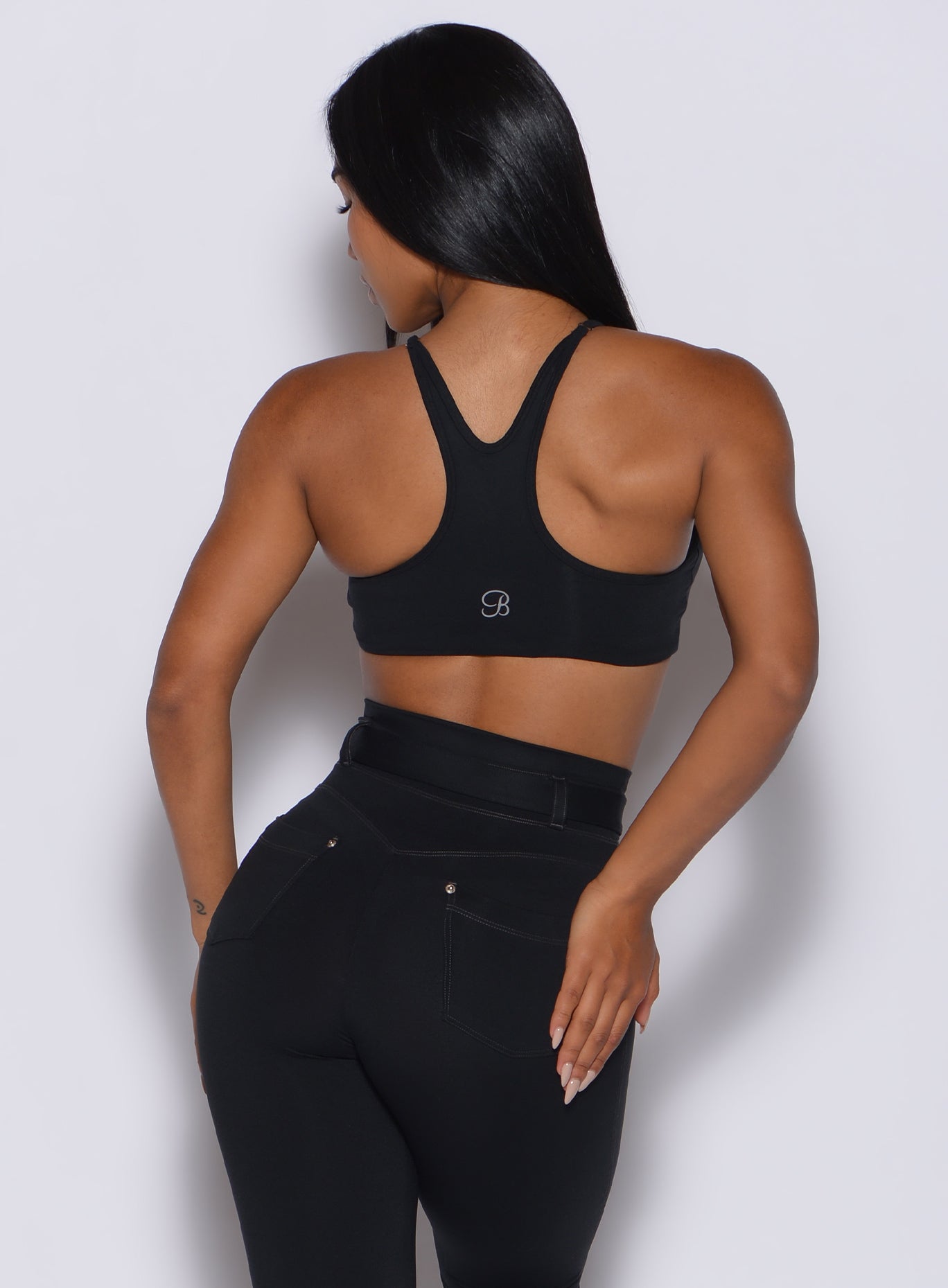 Back profile view of a model wearing our black high neck crop bra and a matching leggings
