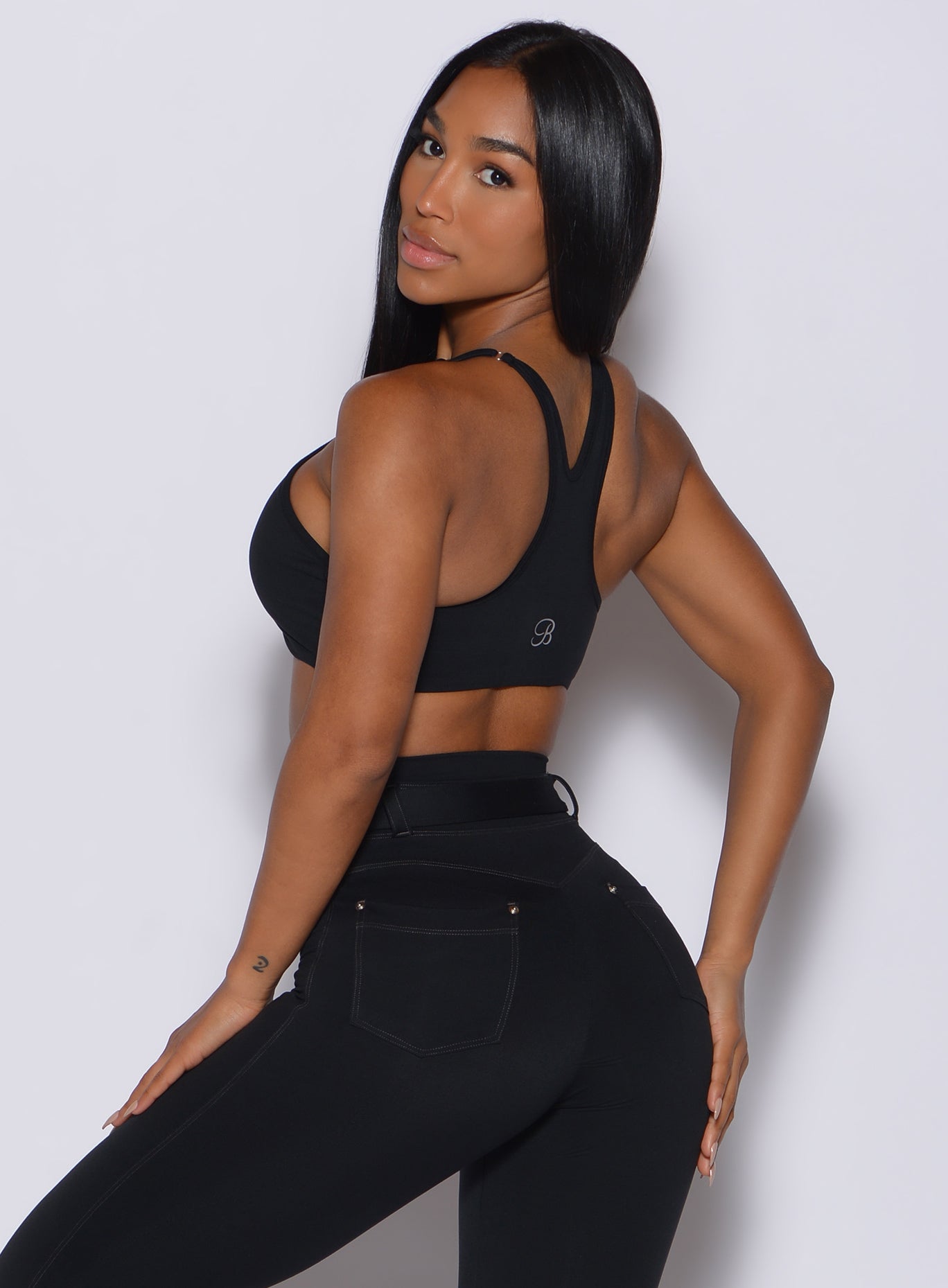 back profile view of a model facing to her left wearing our black high neck crop bra along with a matching leggings 