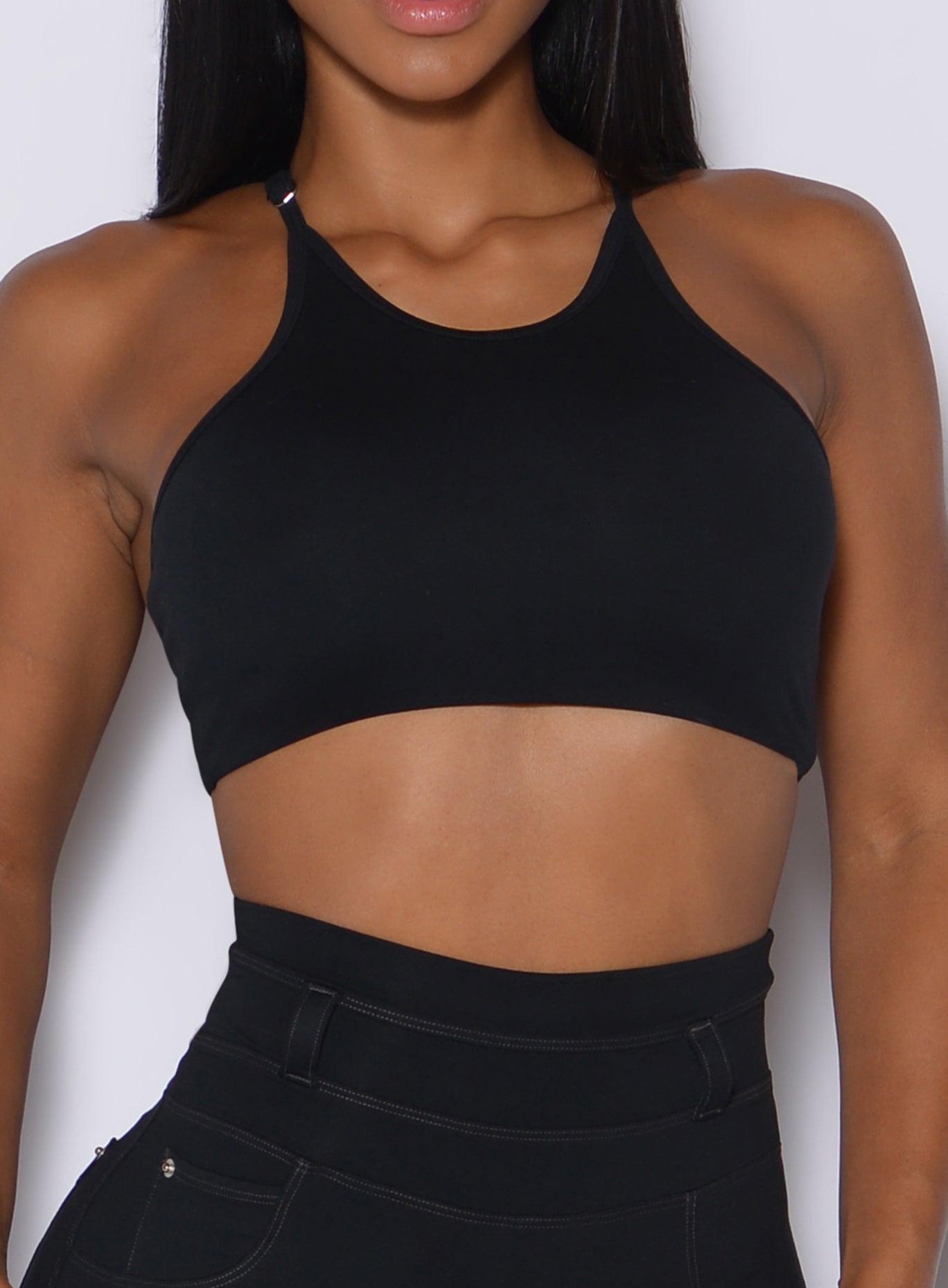 zoomed in front profile view of a model wearing our black high neck crop bra and a matching leggings