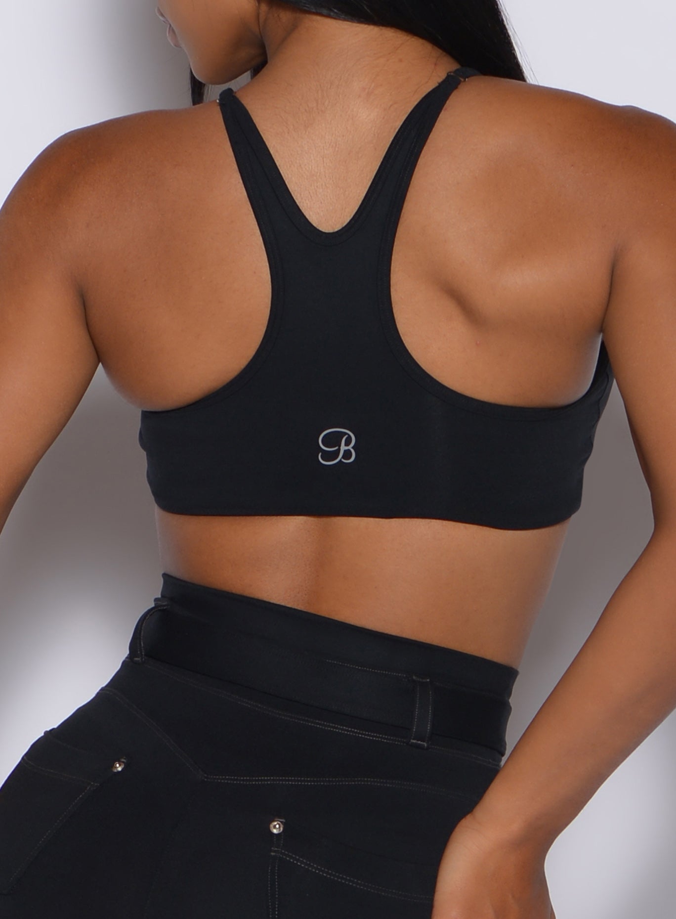 Zoomed in back profile view of a model wearing our black high neck crop bra and a matching leggings