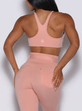 Back profile view of a model wearing our high neck crop bra in pale blush color along with a matching leggings