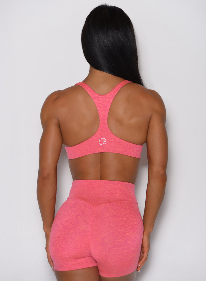 A rear view of the model wearing our Hyper Form Bra in Neon Tangerine Punch.