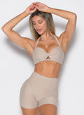 front profile view of a model with both hands resting on top of her head wearing the Infinity Bandeau in taupe color