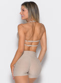 back profile view of a model facing to the left side wearing the Infinity Bandeau in taupe color
