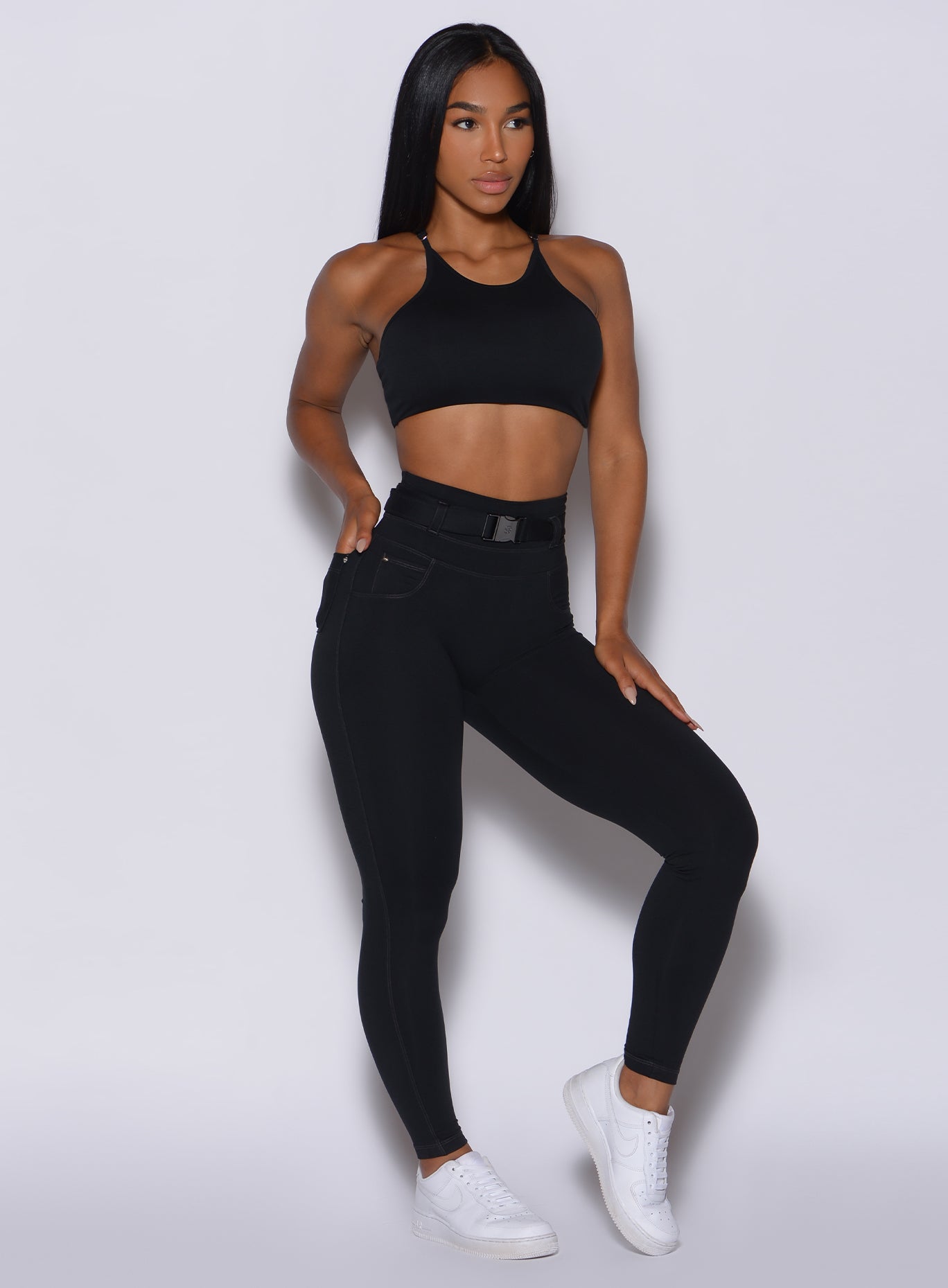 front profile view of a model wearing our black peach bottoms leggings along with the matching sports bra 