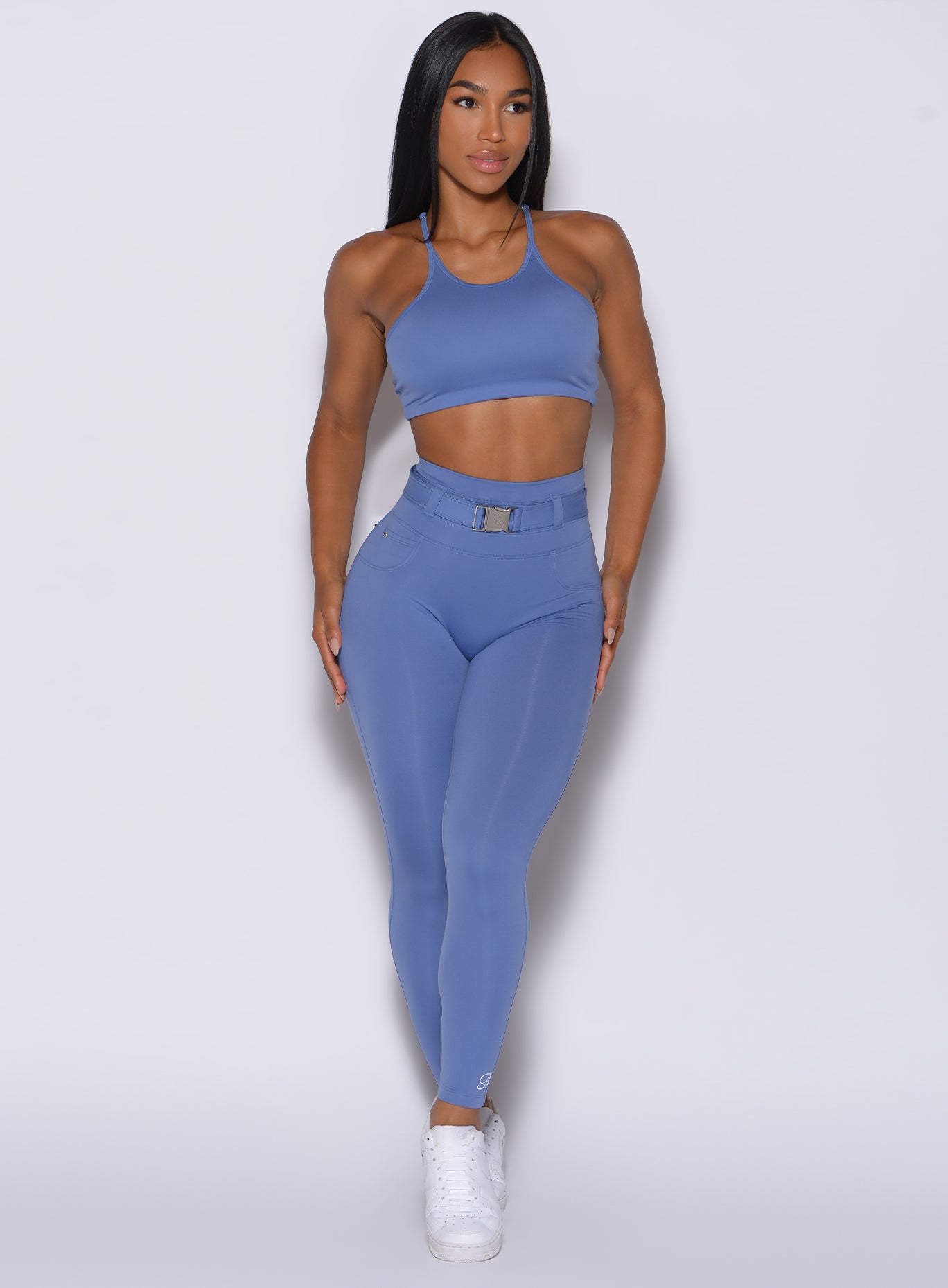 front  profile view of a model wearing our peach bottoms leggings in denim blue color along with the matching sports bra
