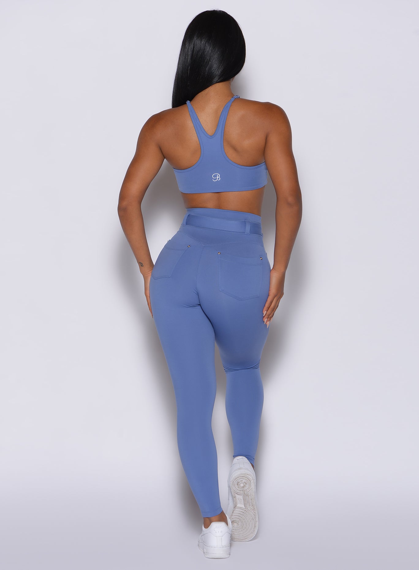 back profile view of a model wearing our peach bottoms leggings in denim blue color along with the matching sports bra