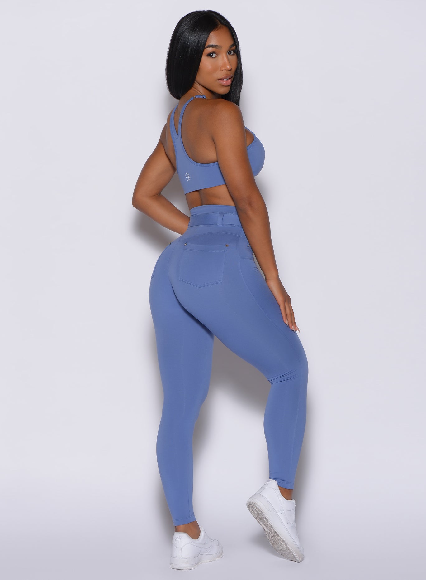 Right side  profile view of a model wearing our peach bottoms leggings in denim blue color along with the matching bra