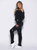 left side profile view of a model wearing the Luxe Leg Warmers in black color paired with the matching top and leggings
