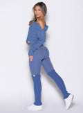 left side profile view of a model looking over her shoulder wearing the Luxe Leg Warmers in blue chill color