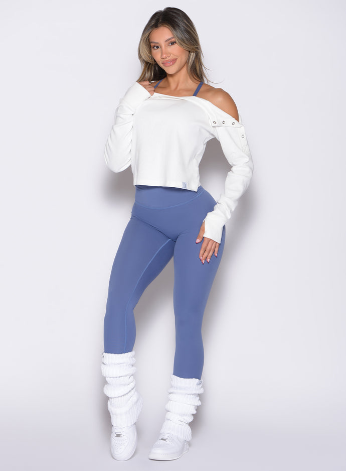 front profile view of a model wearing the Internal Scrunch Leggings in blue chill color paired with white leg warmers and pullover