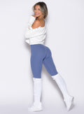 left side profile view of a model wearing the Luxe Leg Warmers in white color paired with the matching pullover