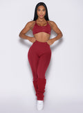 front profile view of a model holding the waistband of the leggings wearing the Luxe Leg Warmers in red velvet color