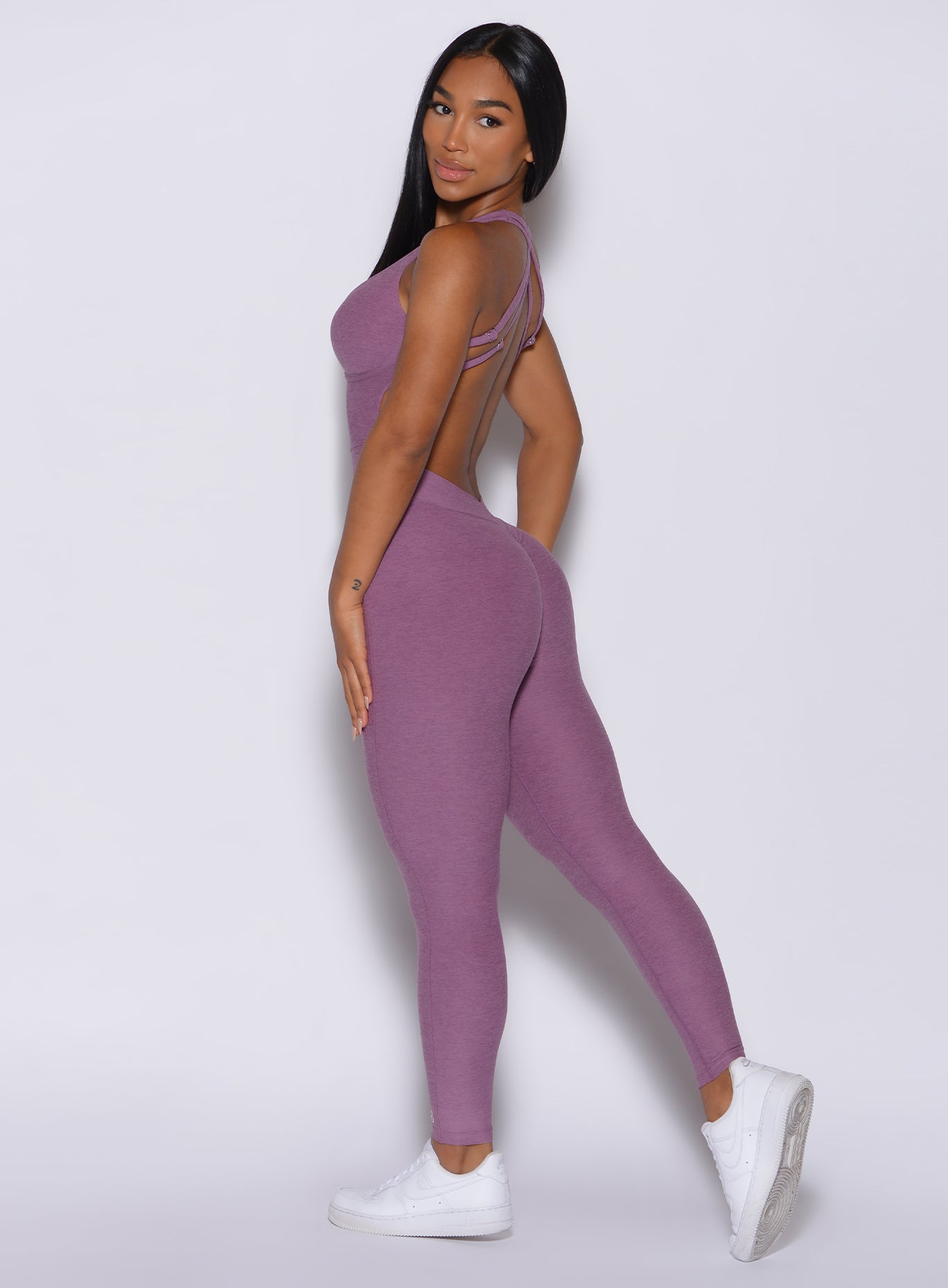 Left side profile view of a model facing to her left wearing our lavender bombshell bodysuit