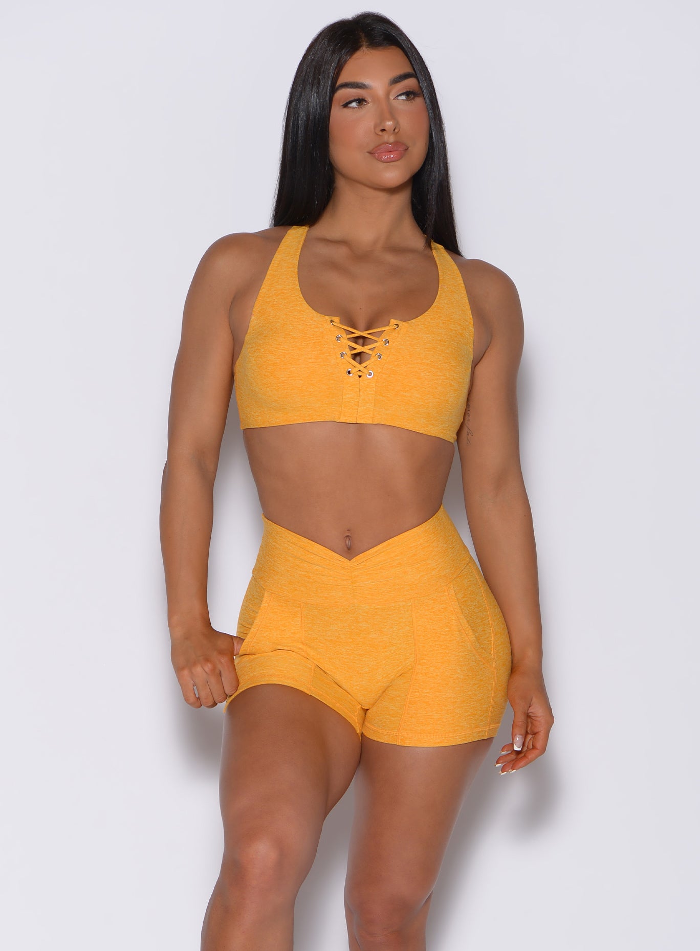 Front profile view of a model in our laced crop bra in sunkissed color and a matching shorts 