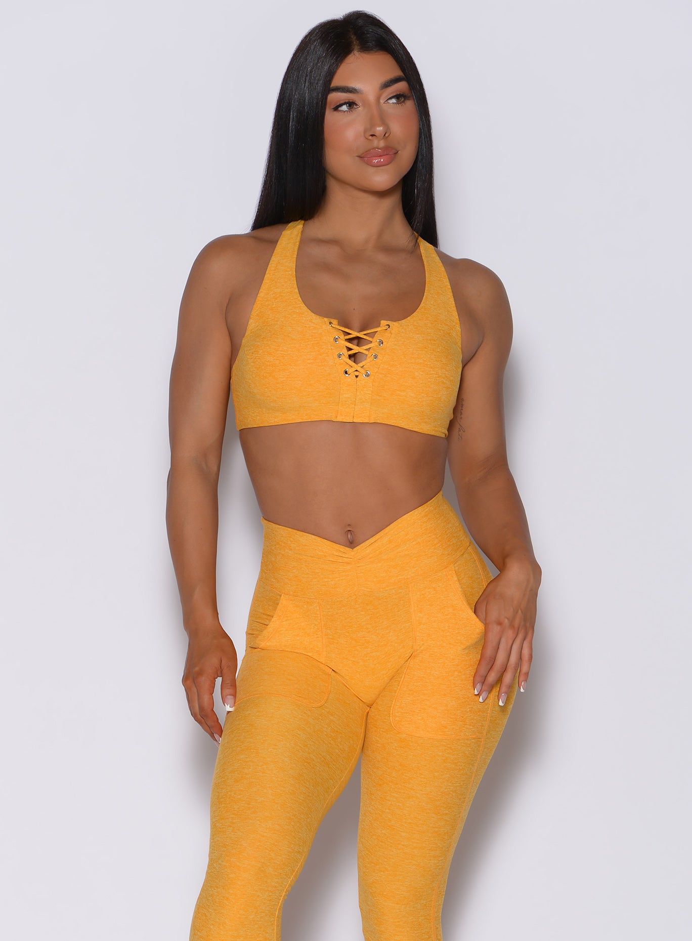 Front  profile view of a model wearing our laced crop bra in sunkissed color and a matching leggings
