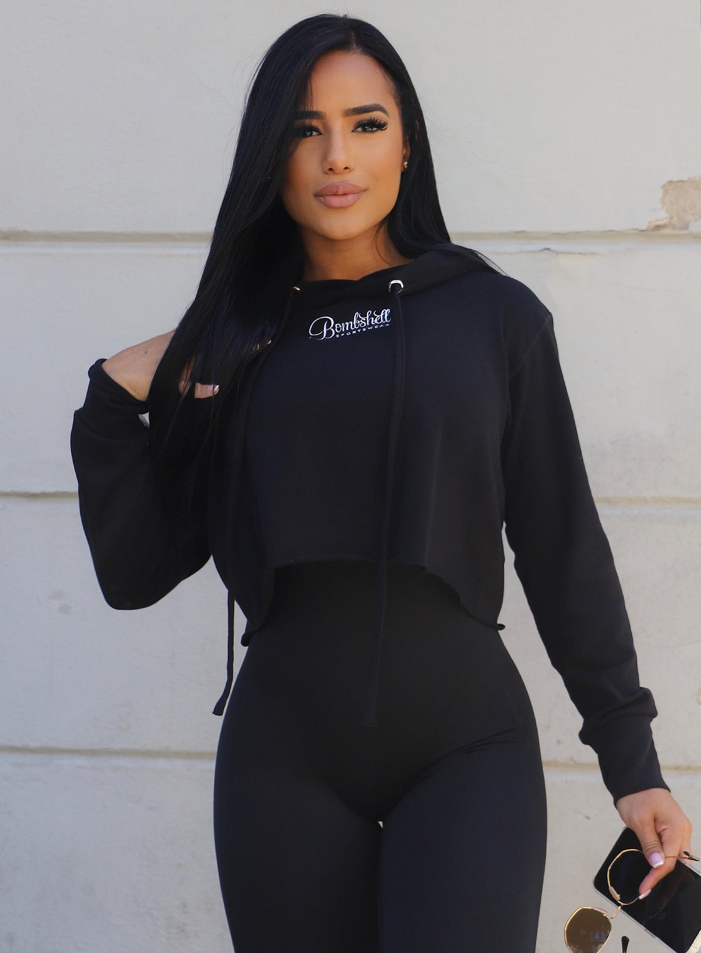 front view of female wearing the bombshell logo hoodie with a one piece bodysuit