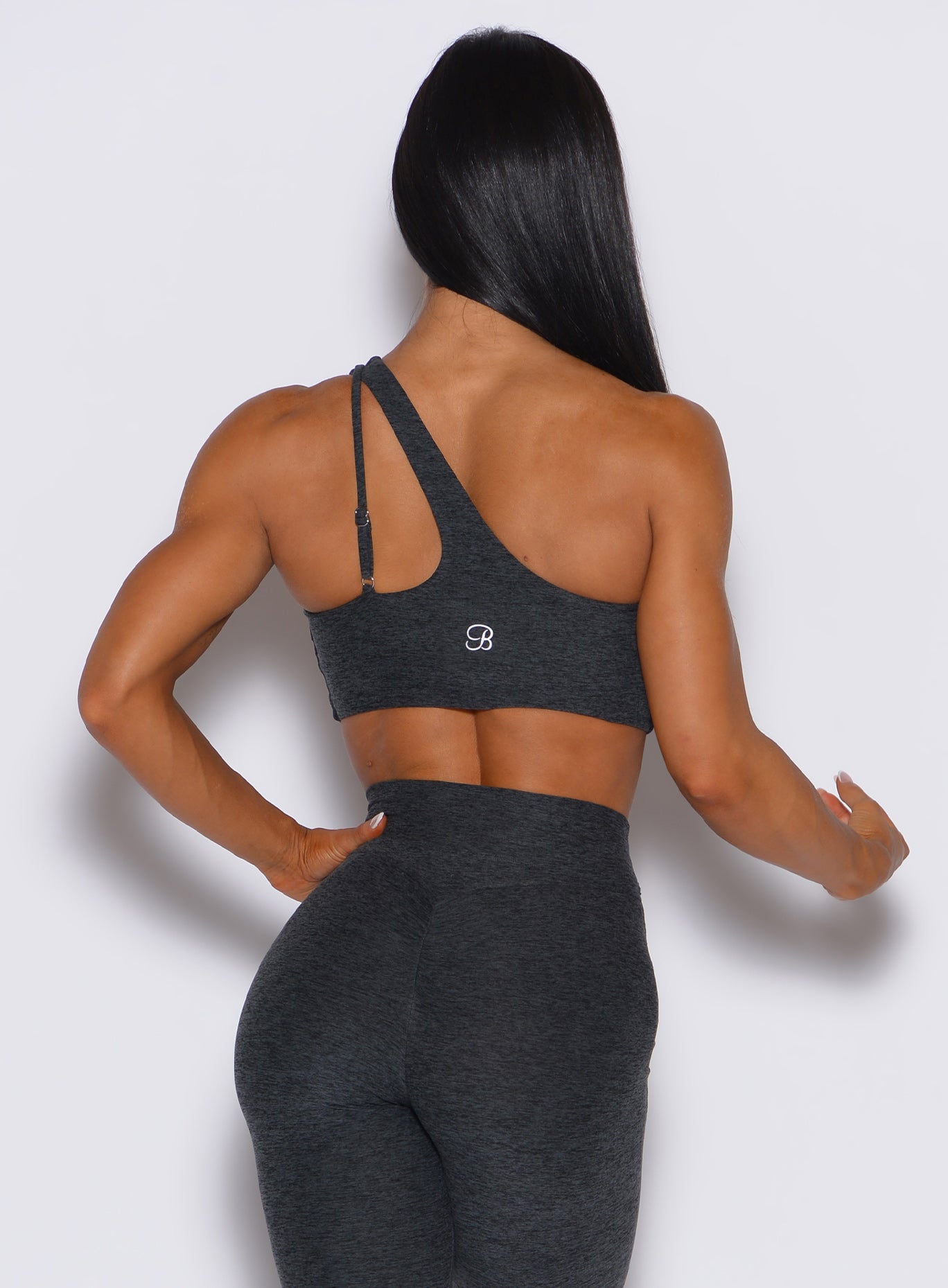back profile view of a model wearing our lateral top in charcoal color along with a matching leggings