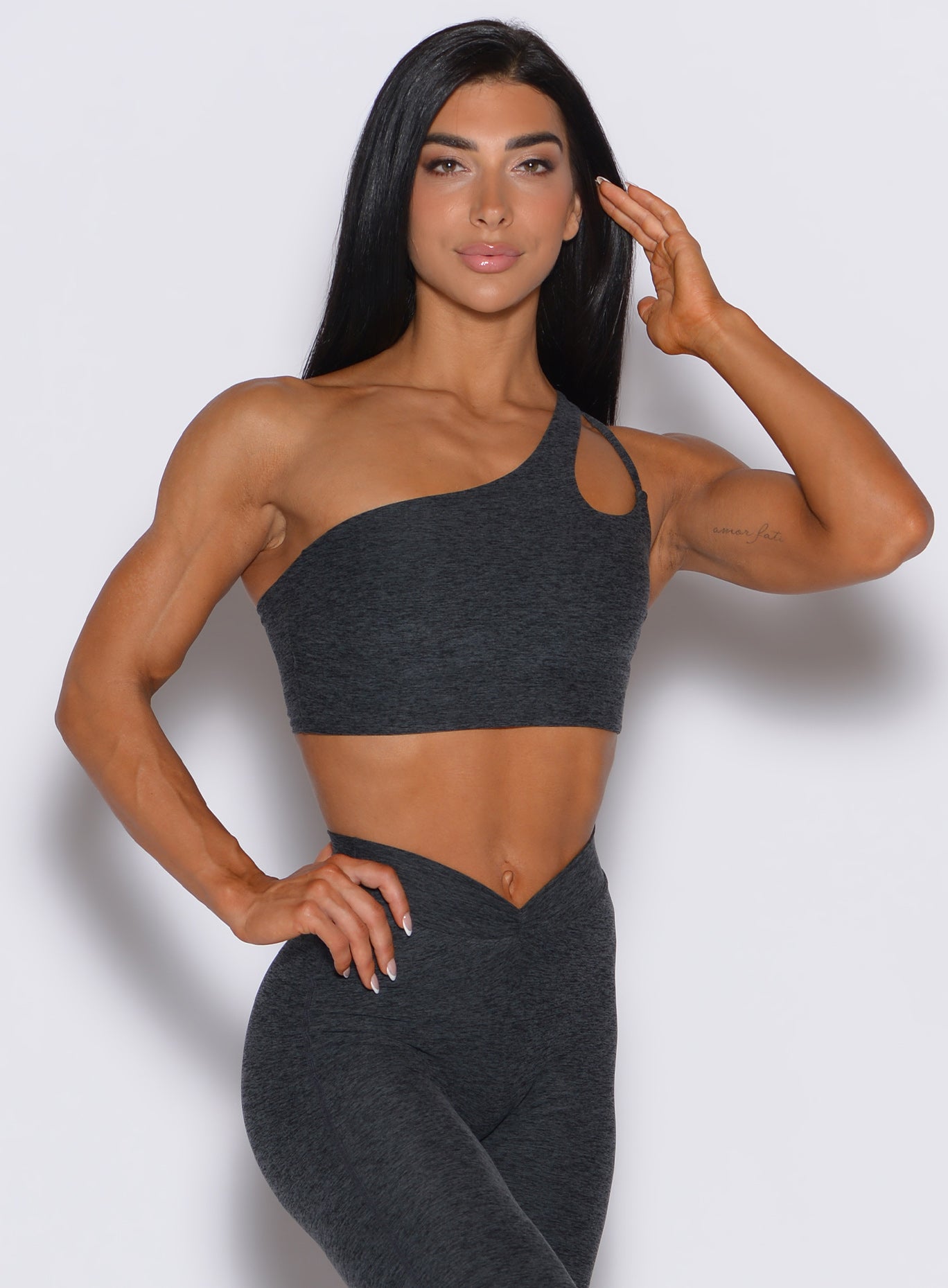 Front profile view of a model wearing our lateral top in charcoal color along with a matching leggings 