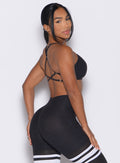 back right side profile view of a model looking over her shoulder wearing the Lift Luxe Sports bra in Heathered black color