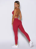 left side profile view of a model looking over her shoulder wearing the Line Contour Leggings in maroon color 