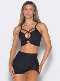 Woman wearing a black sports bra and shorts set on a light gray background