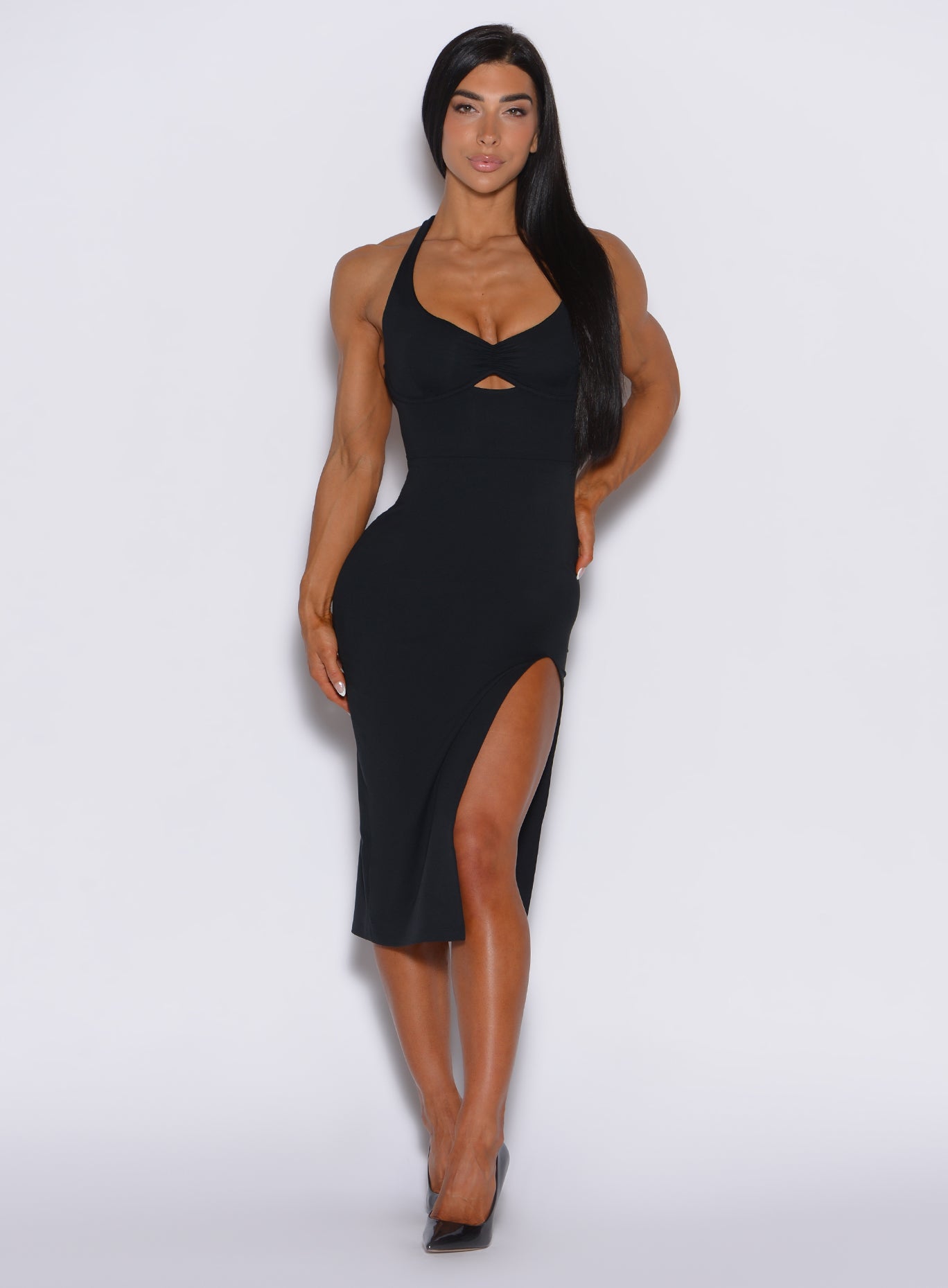 front  profile view of a model facing forward  wearing our black dress with a  high side slit on the left