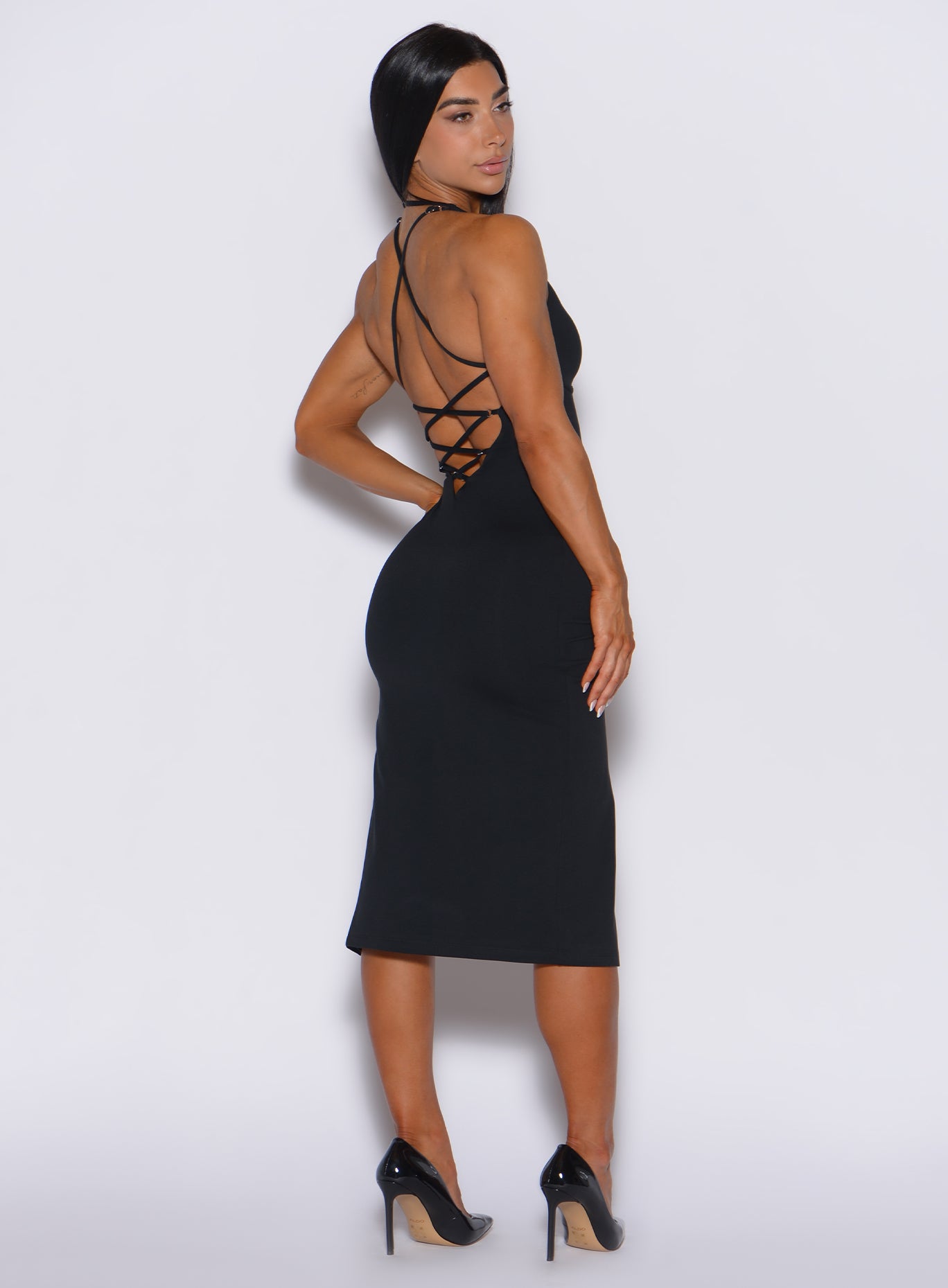 back profile view of a model wearing our black dress with a criss cross design at the back  